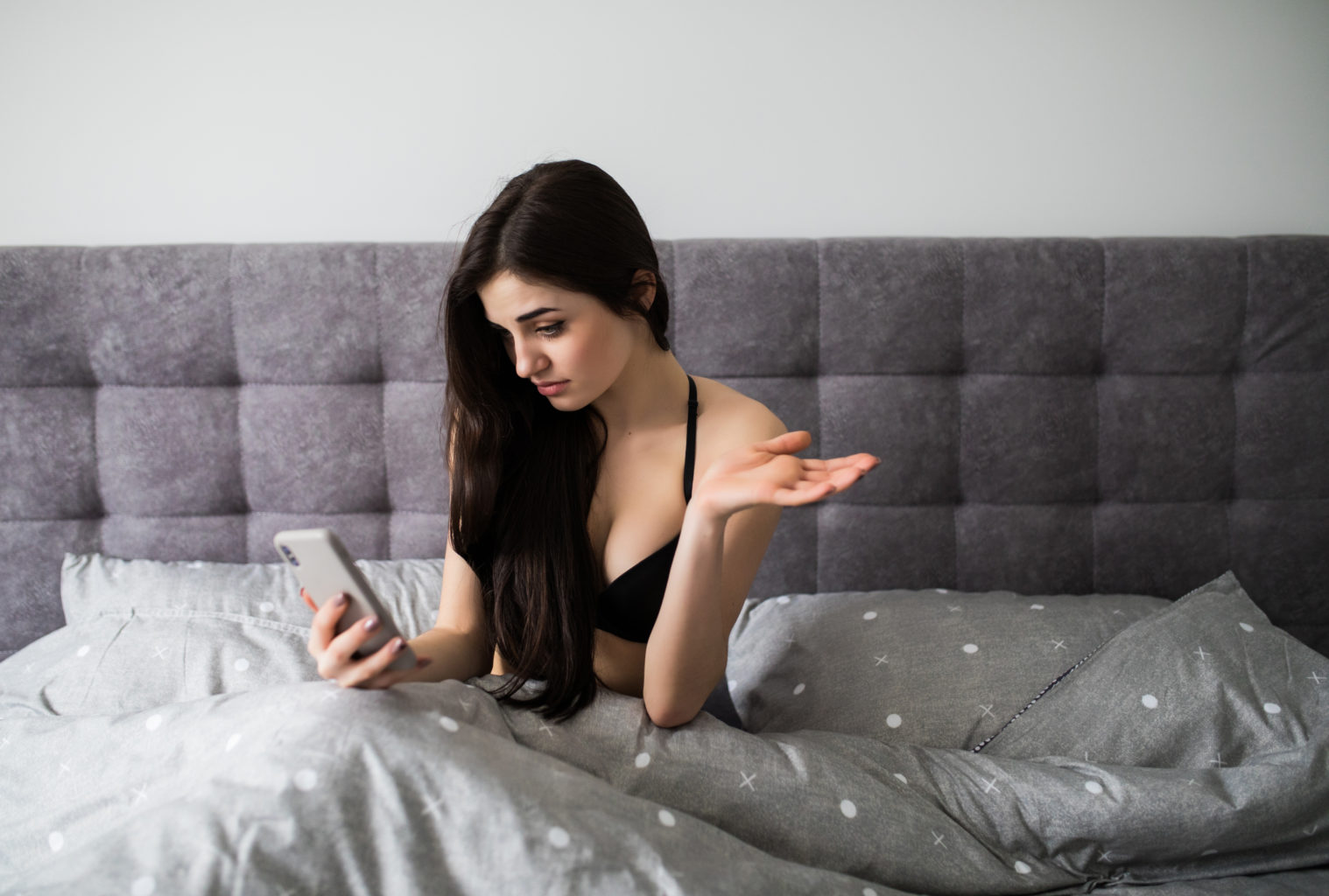 Девојка на телефон во кревет гледа порно